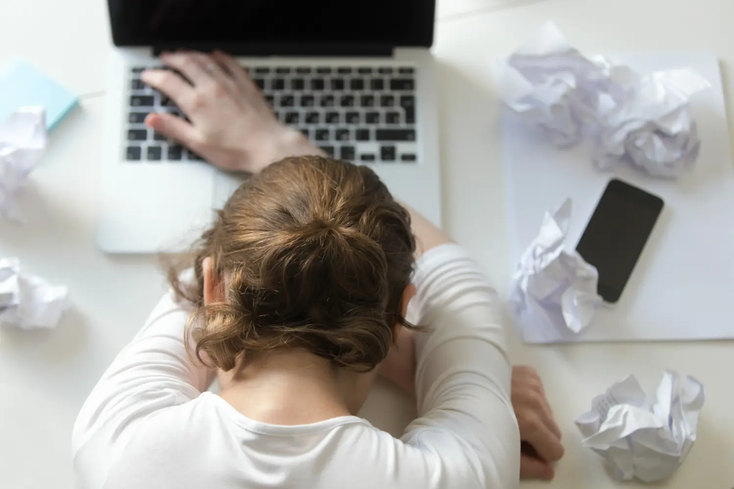 Una persona trabajadora padeciendo estres laboral con su computadora en su escritorio
